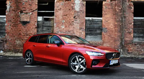Czerwone Volvo V60 na tle starej ceglanej ściany. Wiele osób szuka volvo v60 opinie, ten model wygląda świetnie.