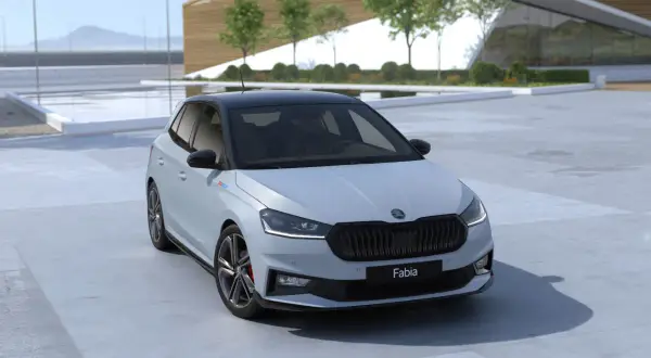Nowa Skoda Fabia 2026 w jasnym kolorze z czarnym dachem, zaparkowana przed nowoczesnym budynkiem.