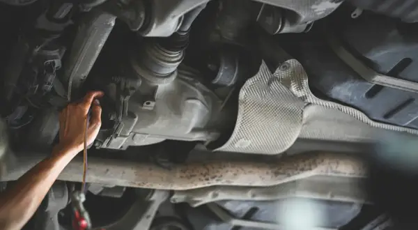 Ręka mechanika sprawdza olej w skrzyni biegów samochodu.