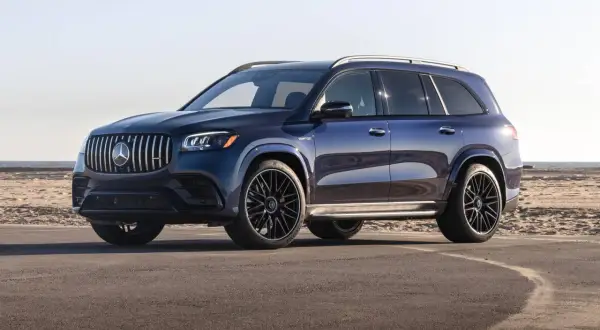 Lśniący, granatowy Mercedes-Benz GLS z czarnymi felgami stoi na asfalcie przy plaży.