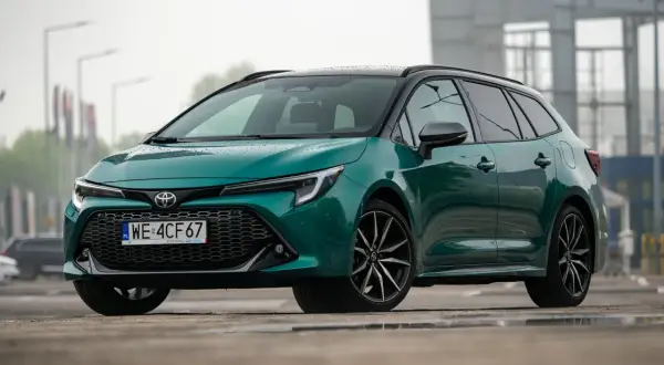 Nowa Toyota Corolla 2025 w kolorze zielonym, z czarnym dachem i felgami, prezentuje się stylowo na mokrej nawierzchni.