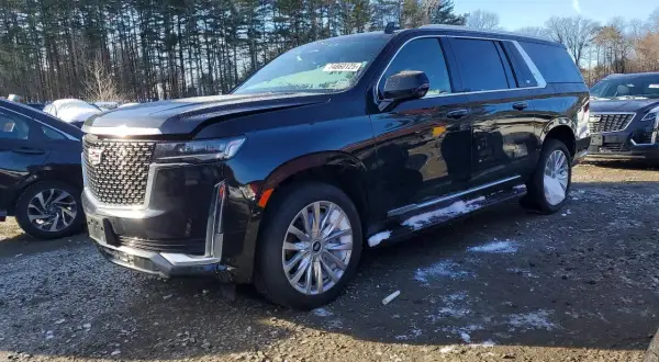 Czarny Cadillac Escalade 2025 z chromowanymi felgami i detalami, zaparkowany na żwirowym placu z resztkami śniegu.