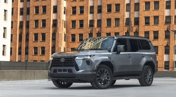 Szary Lexus GX 550 na tle ceglanego budynku.
