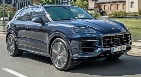 Ciemnoniebieski Porsche Cayenne jedzie po mieście. Sprawdź aktualną porsche cayenne cena.