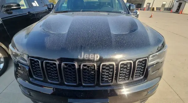 Czarny Jeep Limited, pokryty kurzem, z charakterystycznym grillem i logo Jeep.