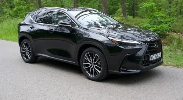 Czarny Lexus NX 350h na tle leśnej drogi. Elegancki SUV z charakterystycznym grillem i nowoczesnymi światłami.