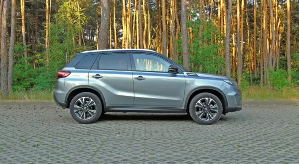 Szary Suzuki Vitara na tle lasu. Wiele osób szuka **Suzuki Vitara opinie** przed zakupem, a ten model wygląda obiecująco.