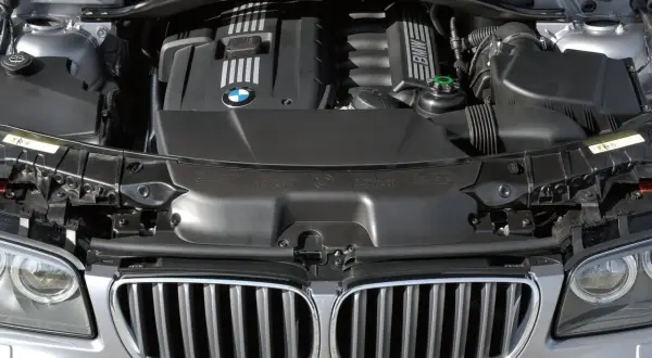 Silnik BMW X3 E83, widok z góry. Czarna pokrywa silnika z logo BMW.