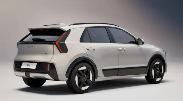 Nowy Kia Niro w kolorze jasnoszarym, widok z tyłu i boku. Stylowe światła LED i czarne detale podkreślają nowoczesny design.