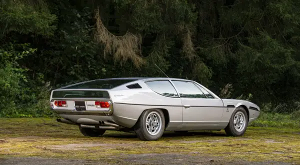 Srebrny Lamborghini Espada z lat 70. na tle zieleni. Klasyk motoryzacji.