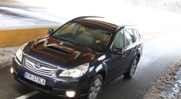 Ciemny Subaru Outback 2025 jedzie przez tunel, kierowca w szaliku.