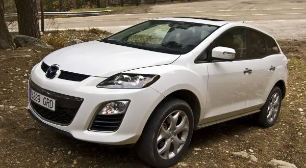 Biała Mazda CX7 zaparkowana na leśnej drodze.