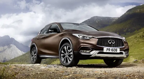 Brązowy Infiniti QX30 na kamienistej drodze w górach.
