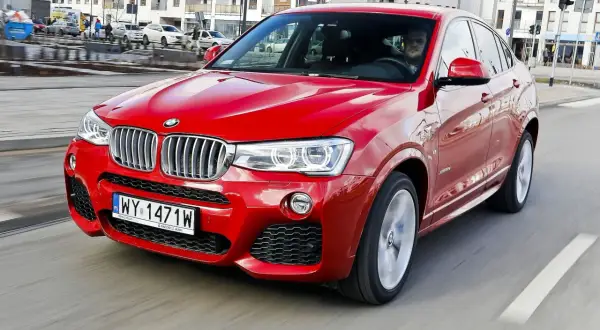 Czerwone BMW X4 2025 pędzi ulicą, błyszcząc w słońcu. Kierowca w środku, gotowy na przygodę.