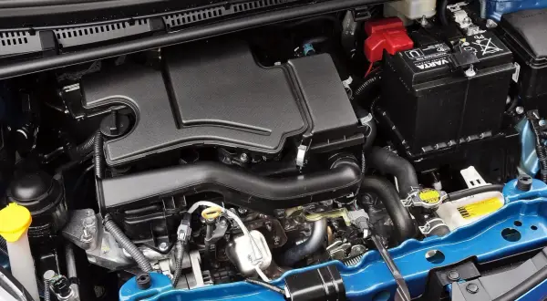 Silnik Toyoty Yaris 2017: czarny plastikowy osłona, akumulator Varta, niebieska belka.