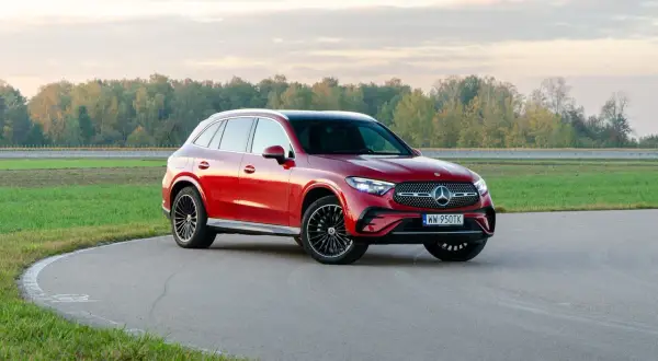 Czerwony Mercedes-Benz GLC 300 na zakręcie toru wyścigowego, z jesiennym lasem w tle.