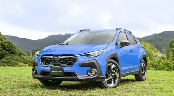 Niebieski Subaru XV Crosstrek na tle zielonych wzgórz. Gotowy na przygodę w terenie.