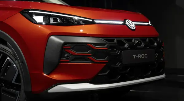 Pomarańczowy Volkswagen T-Roc z nowoczesnymi światłami IQ.LIGHT i charakterystycznym grillem.