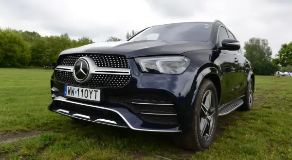 Ciemnoniebieski Mercedes GLE 450 stoi na trawie, z przodem skierowanym w stronę widza.