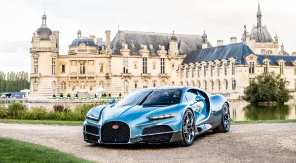 Błękitne Bugatti Chiron przed zamkiem. Zastanawiasz się, ile kosztuje Bugatti? To marzenie wielu, ale cena jest astronomiczna.