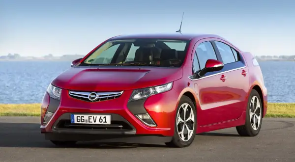 Czerwony Opel Ampera stoi nad jeziorem, gotowy na ekologiczną podróż.