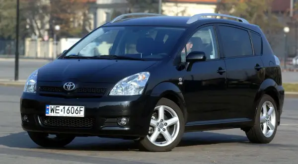 Czarna Toyota Corolla Verso z relingami dachowymi, zaparkowana na ulicy.