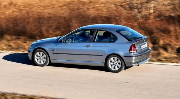 Srebrne BMW Compact w ruchu, z rozmytym tłem.