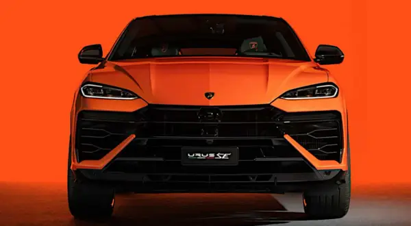 Pomarańczowy Lamborghini Urus SE z przodu, z czarnymi detalami i agresywnym grillem, na tle jaskrawej pomarańczy.