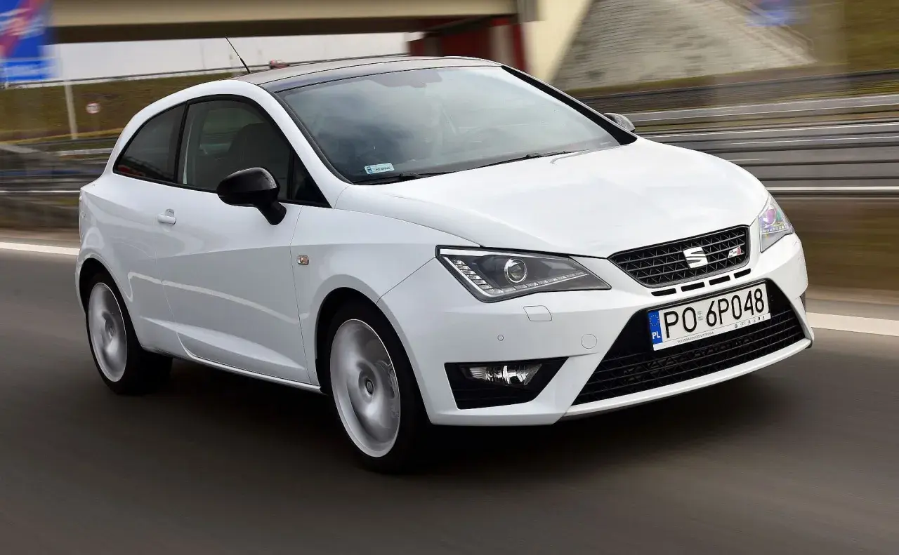 Biały Seat Ibiza 1.4 benzyna w ruchu, z czarnym dachem, na drodze.