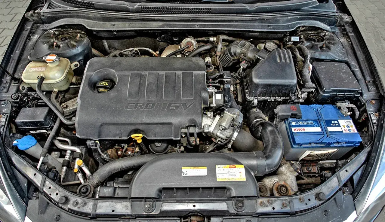 Silnik Kia Ceed 1.6 CRDi. Widoczny jest czarny plastikowy kolektor, akumulator Bosch i zbiornik płynu chłodniczego.