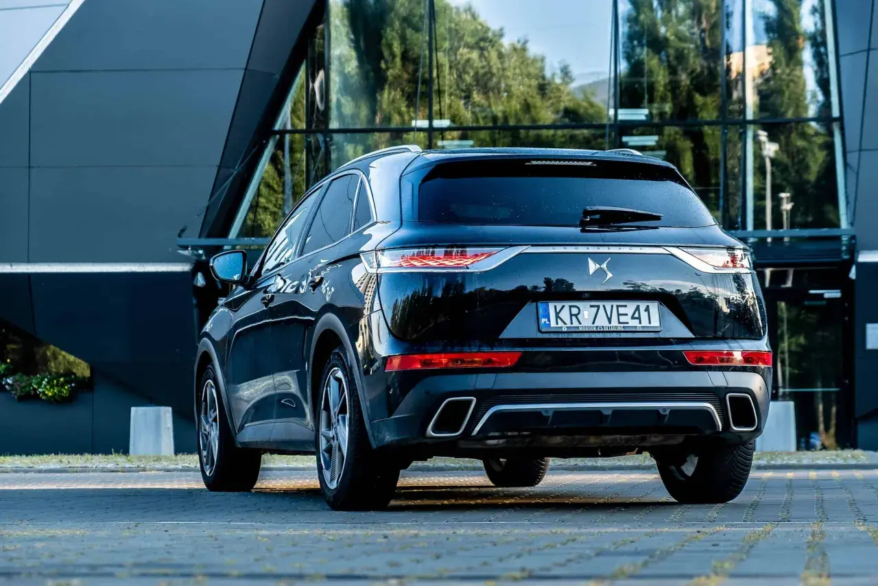 Elegancki czarny Citroën DS7 Crossback z polskimi tablicami rejestracyjnymi stoi przed nowoczesnym budynkiem.