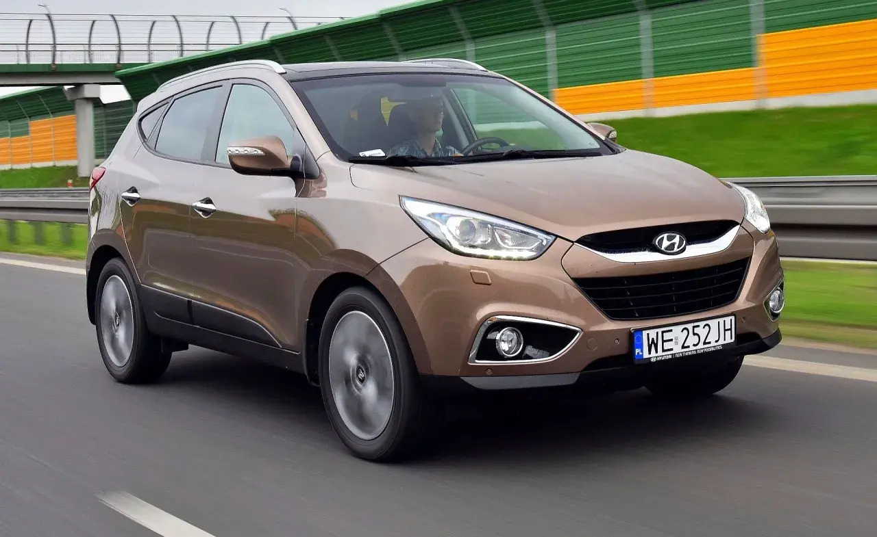 Brązowy Hyundai ix35 w ruchu drogowym, z widocznym kierowcą.