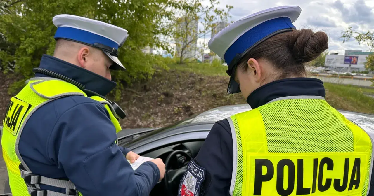 Policjanci w kamizelkach odblaskowych sprawdzają dokumenty, być może wystawiają mandaty za prędkość.