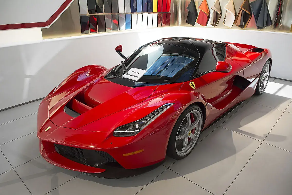 Czerwone Ferrari LaFerrari z czarnym dachem, błyszczące w salonie, gotowe do jazdy.