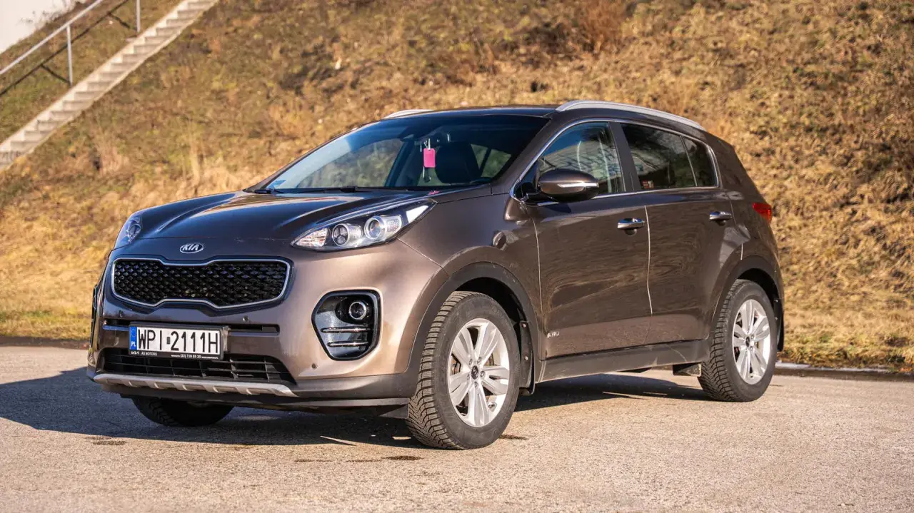 Brązowy Kia Sportage 2020 zaparkowany na drodze, z widocznymi schodami w tle.