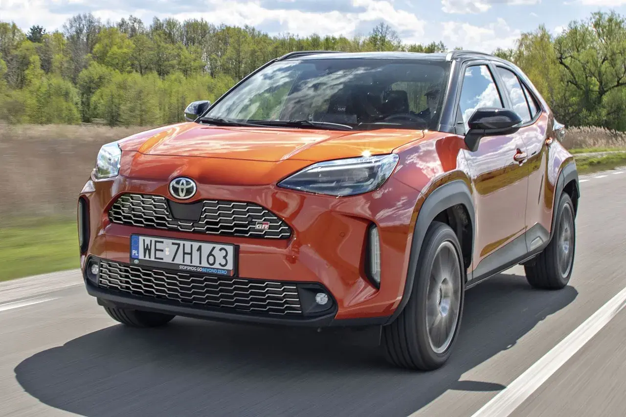 Pomarańczowy Toyota Yaris Cross GR Sport na drodze. Sprawdź aktualną toyota yaris cross cena i dostępne wersje.
