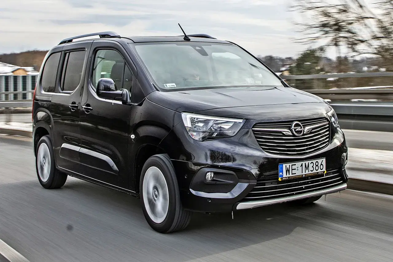 Czarny Opel Combo Life pędzi po drodze, gotowy na rodzinne przygody.