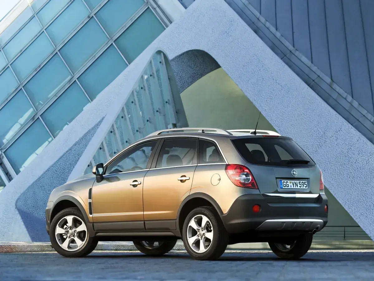 Złoty Opel Antara z nowoczesnym budynkiem w tle.