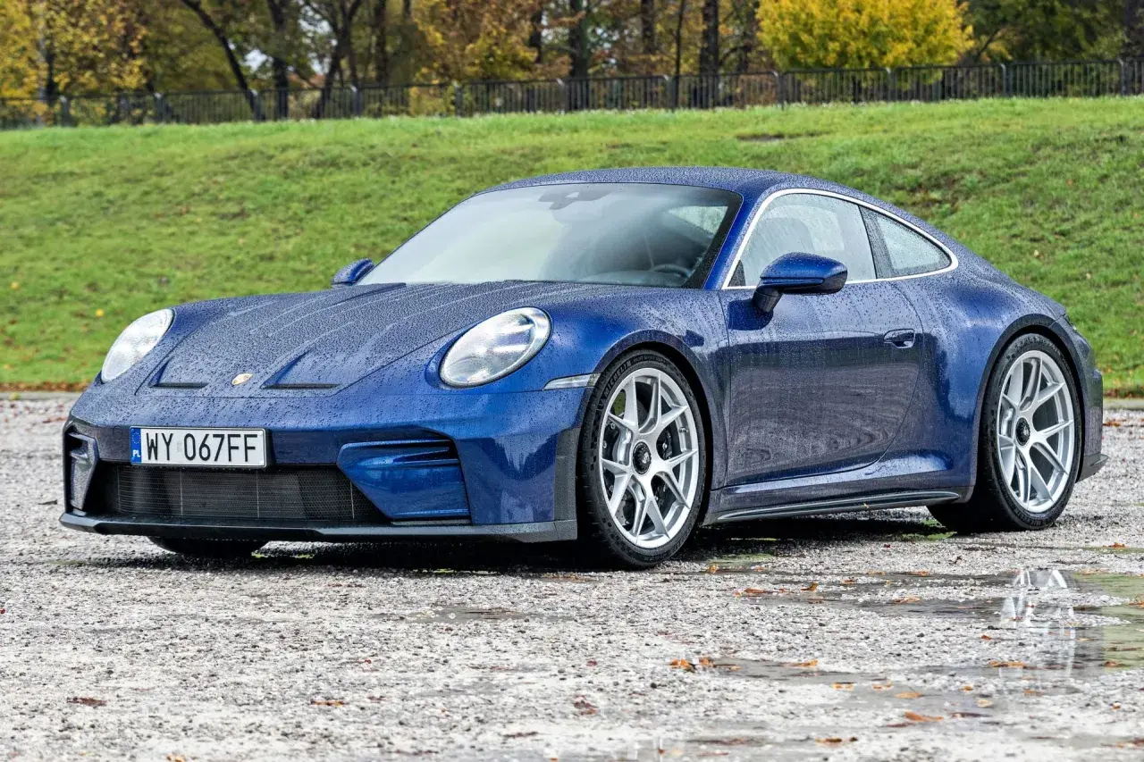Niebieski Porsche 911 na mokrej nawierzchni. Zastanawiasz się nad porsche 911 cena?