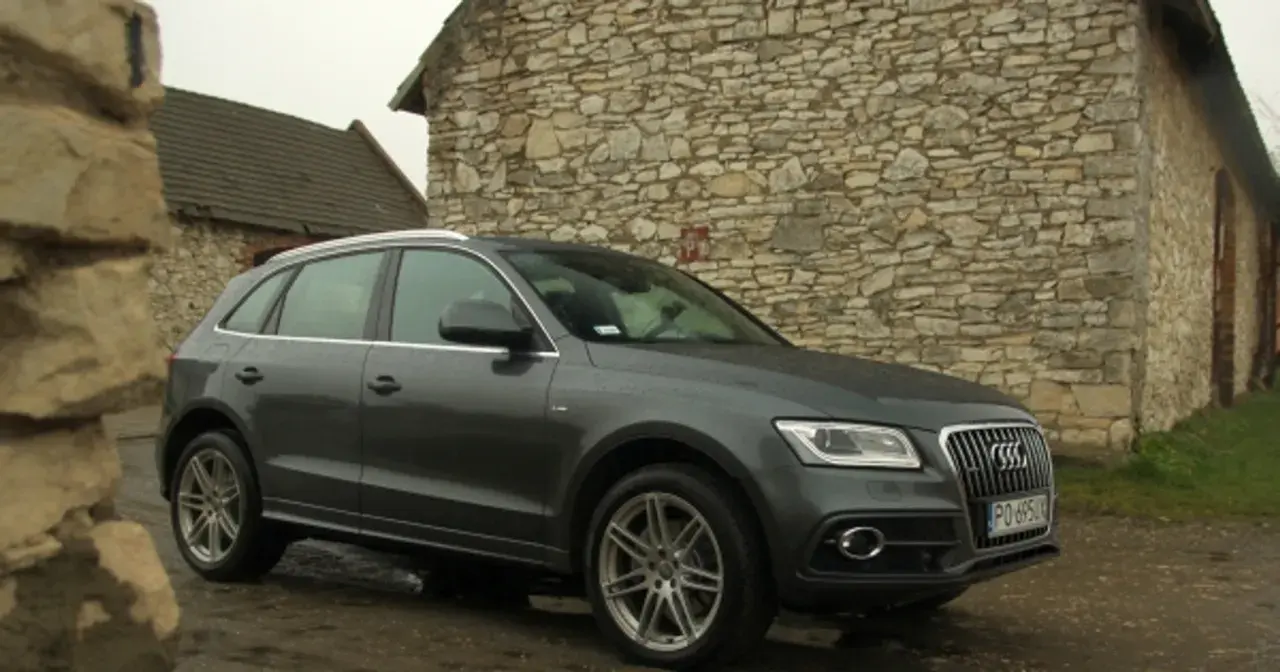 Szary Audi Q5 Quattro zaparkowany przy kamiennym budynku.