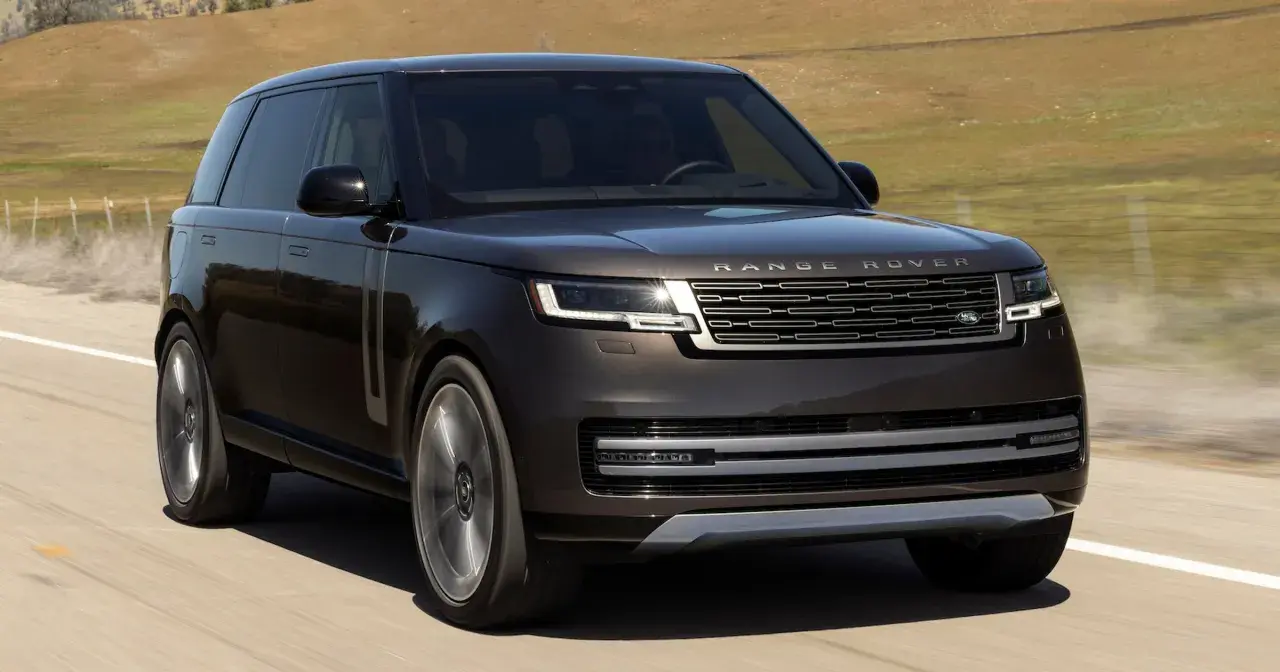 Elegancki, ciemnobrązowy Range Rover 2025 pędzi po pustej drodze, otoczony suchymi, pagórkowatymi krajobrazami.