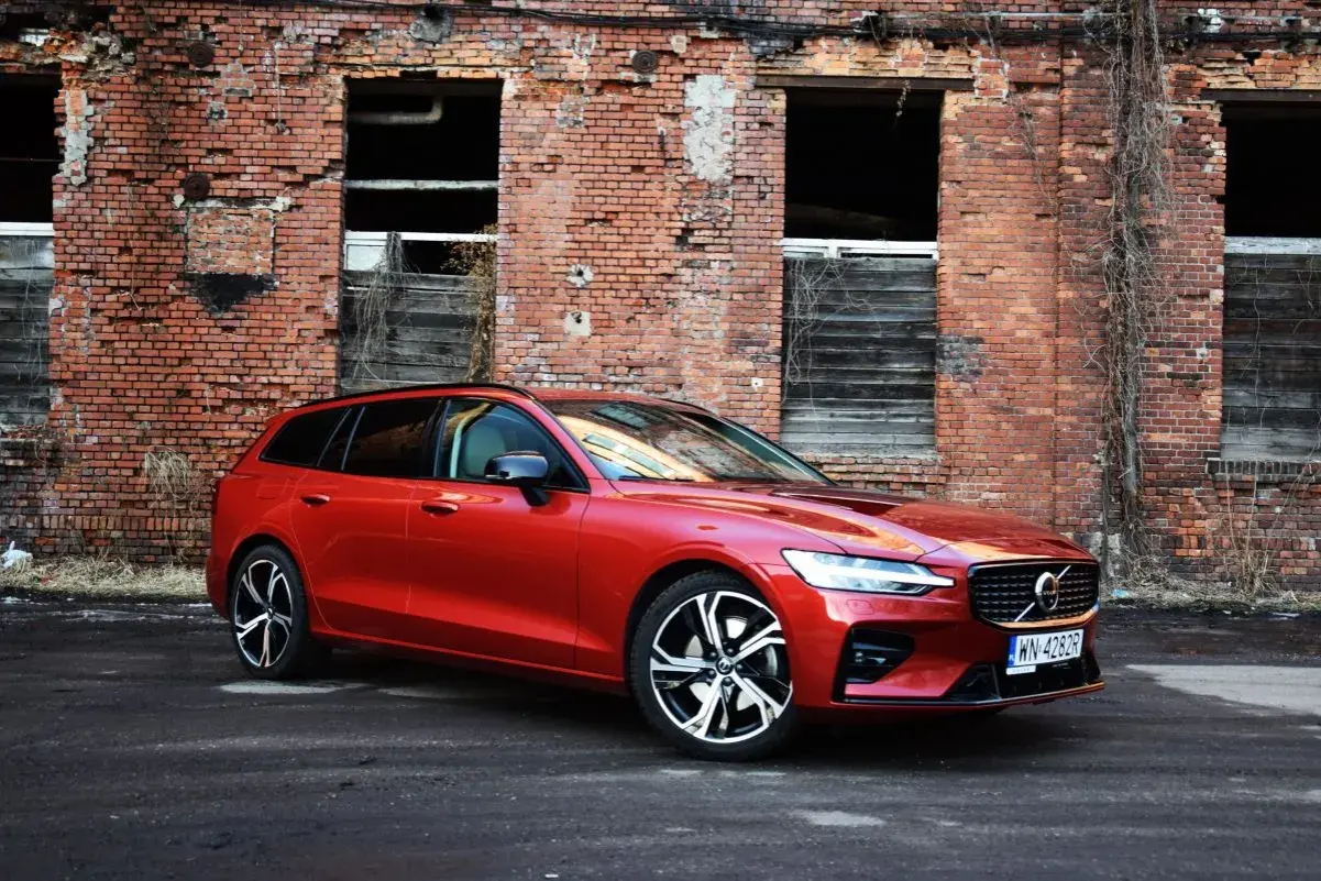 Czerwone Volvo V60 na tle starej ceglanej ściany. Wiele osób szuka volvo v60 opinie, ten model wygląda świetnie.