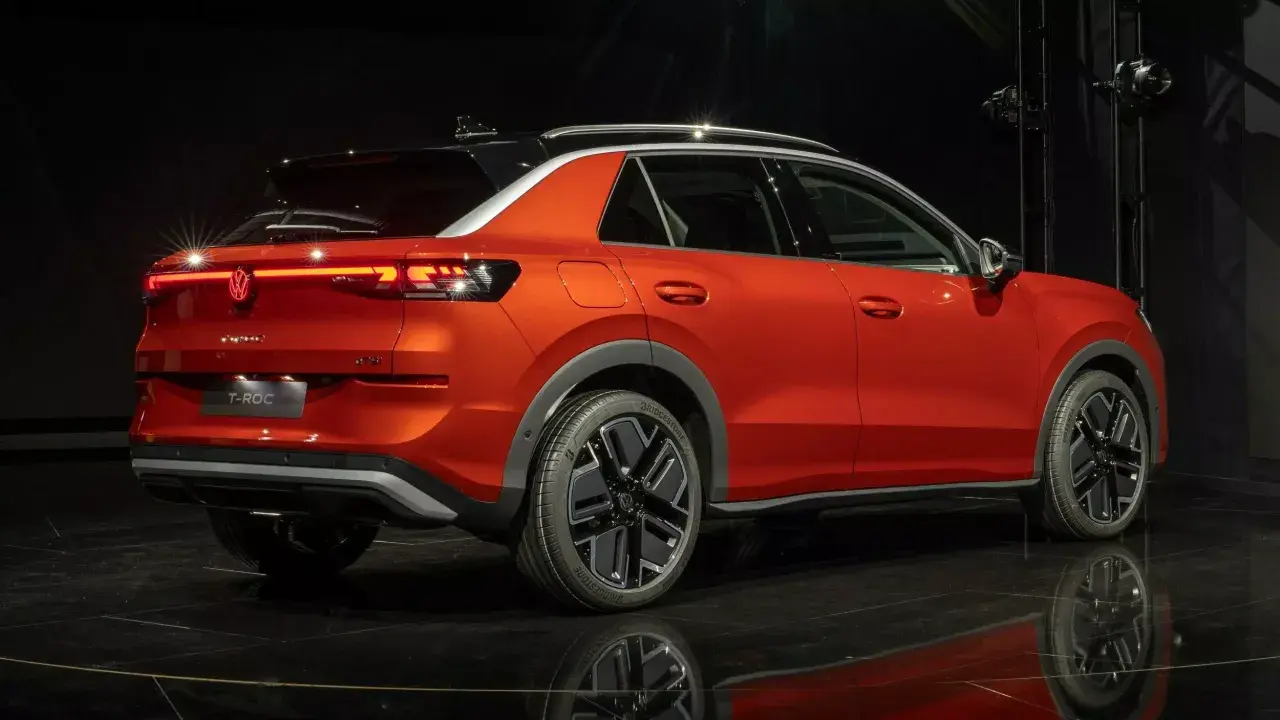 Pomarańczowy Volkswagen T-Roc z czarnym dachem, stylowymi felgami i nowoczesnymi światłami. Sprawdź aktualną volkswagen t-roc cena.