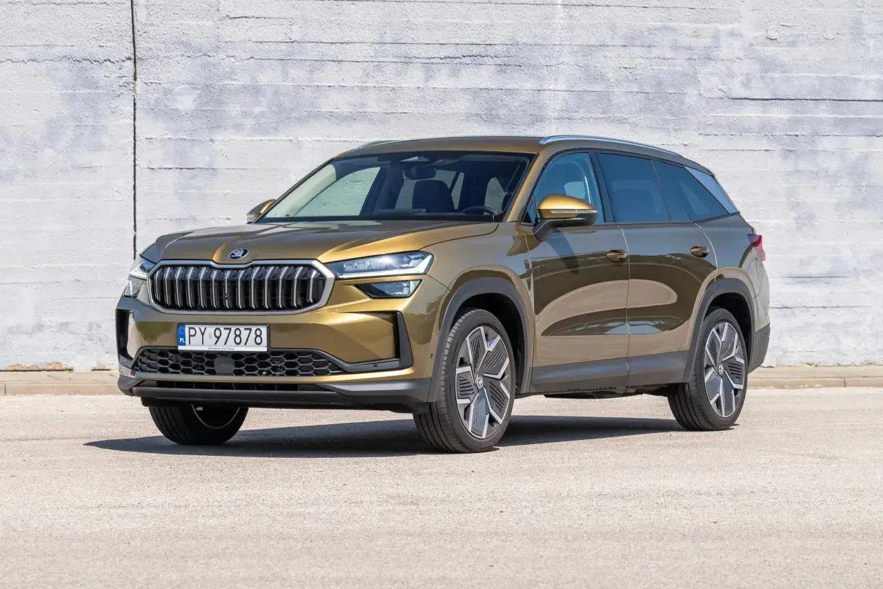 Złoty Skoda Kodiaq stoi przed betonową ścianą. Poznaj jego imponujące skoda kodiaq wymiary, idealne na rodzinne podróże.