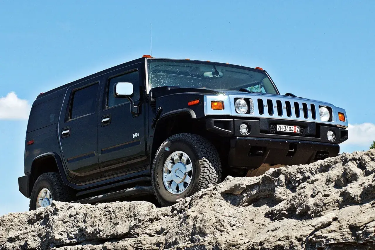 Czarny Hummer H2 pokonuje skalisty teren pod błękitnym niebem.