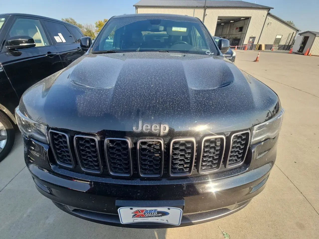 Czarny Jeep Limited, pokryty kurzem, z charakterystycznym grillem i logo Jeep.