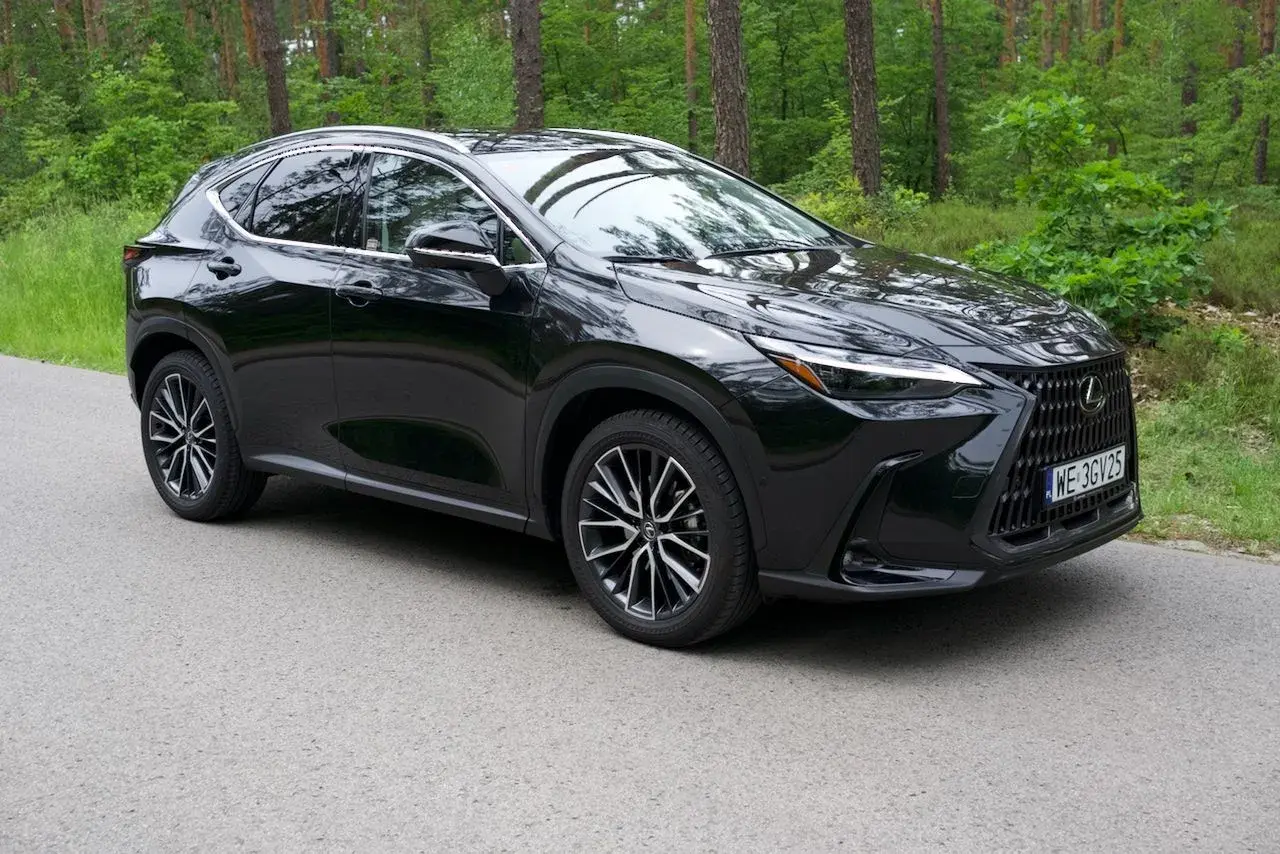 Czarny Lexus NX 350h na tle leśnej drogi. Elegancki SUV z charakterystycznym grillem i nowoczesnymi światłami.