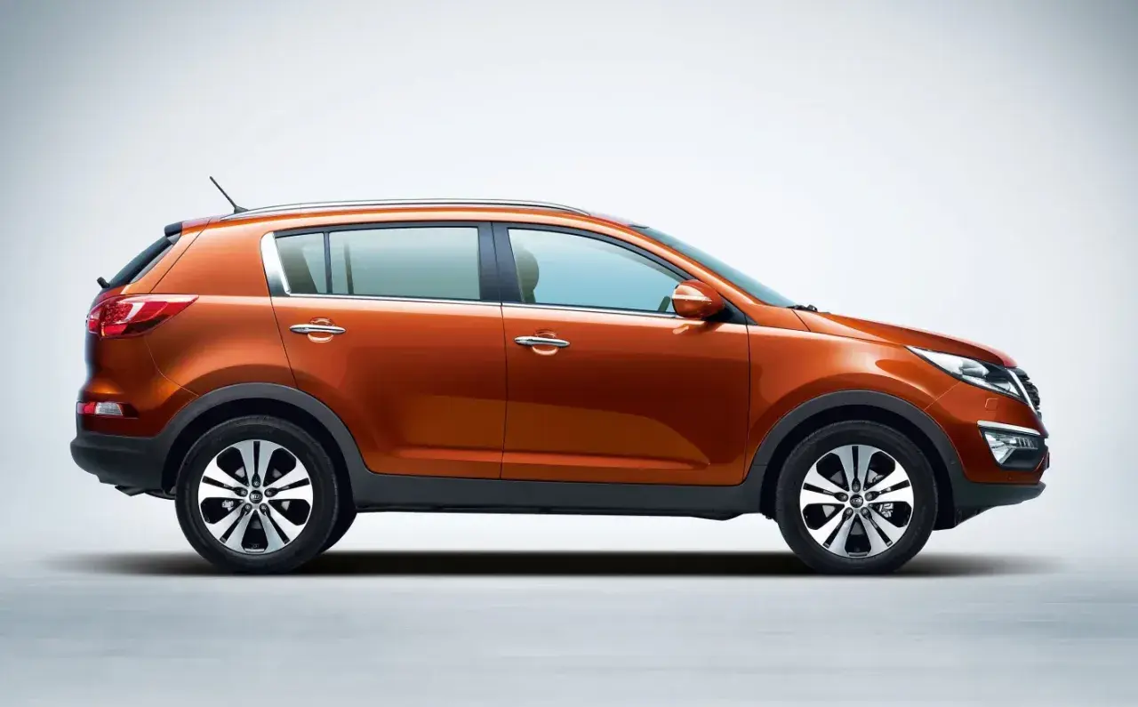 Pomarańczowy Kia Sportage 2015, widok z boku, na jasnym tle. Stylowy SUV gotowy na przygodę.