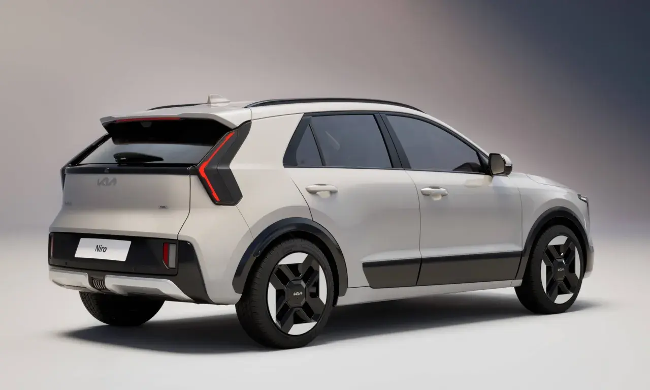 Nowy Kia Niro w kolorze jasnoszarym, widok z tyłu i boku. Stylowe światła LED i czarne detale podkreślają nowoczesny design.