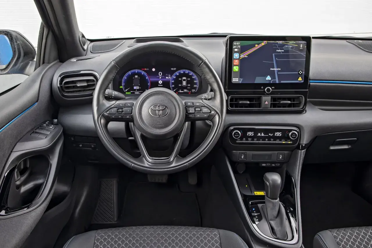 Wnętrze Toyoty Yaris Hybrid. Nowoczesny kokpit z ekranem nawigacji i cyfrowymi zegarami. Sprawdź atrakcyjną toyota yaris hybrid cena.